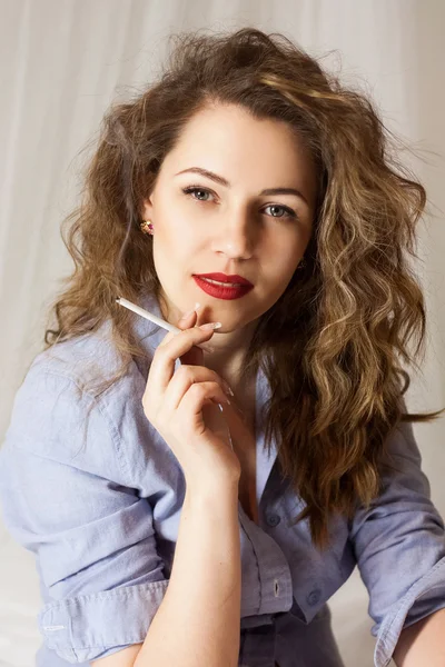 Elegante ragazza emotiva con labbra rosse e capelli ricci sta fumando . — Foto Stock