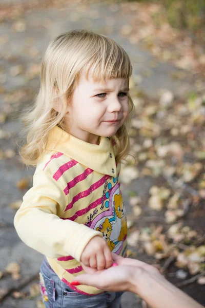 Маленькая девочка берет конфеты из рук матери — стоковое фото