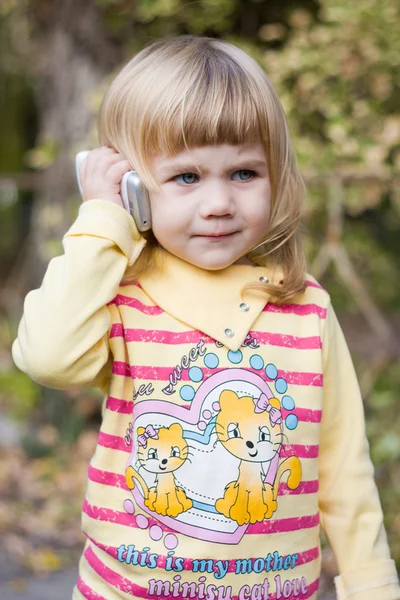 Bir telefonla bir parkta küçük kız — Stok fotoğraf