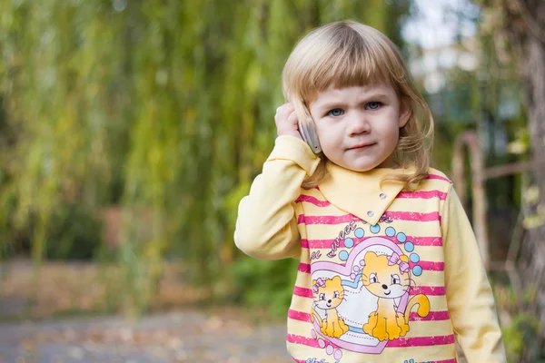 Petite fille avec un téléphone dans un parc — Photo