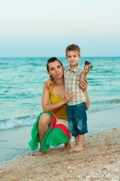 年轻的母亲和她的儿子在沙滩上的贝壳 — 图库照片