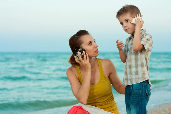 Junge Mutter mit ihrem Sohn am Strand mit Muscheln Stockbild