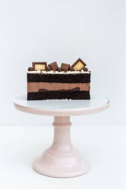 Kurabiyelerle süslenmiş kremalı kek beyaz arka planda beyaz bir standın üzerinde duruyor. İzole edilmiş arka plan. Çocukların doğum günü partisi için lezzetli bir ikram. Hamur işi işçiliği