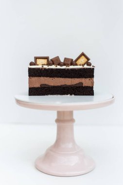 Kurabiyelerle süslenmiş kremalı kek beyaz arka planda beyaz bir standın üzerinde duruyor. İzole edilmiş arka plan. Çocukların doğum günü partisi için lezzetli bir ikram. Hamur işi işçiliği