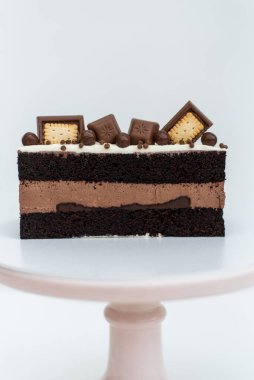 Kurabiyelerle süslenmiş kremalı kek beyaz arka planda beyaz bir standın üzerinde duruyor. İzole edilmiş arka plan. Çocukların doğum günü partisi için lezzetli bir ikram. Hamur işi işçiliği