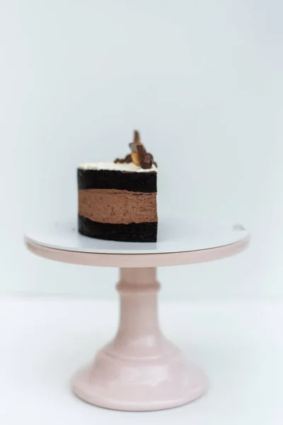 用奶油海绵蛋糕装饰的巧克力蛋糕 白色底座上站着一块饼干 孤立的背景 为孩子们的生日宴会准备的美味的食物 糕点工艺 — 图库照片