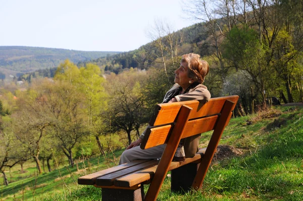 Retiree sitting alone on park bench — Stock Photo, Image