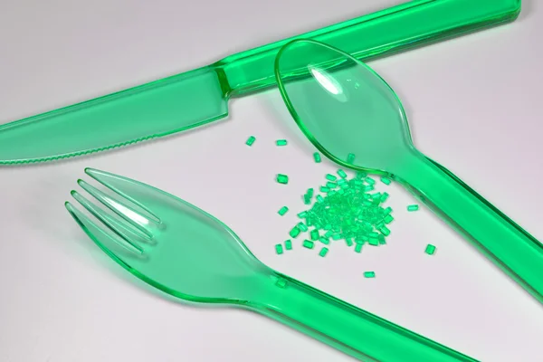 Plastic cutlery with raw material — Stock Photo, Image