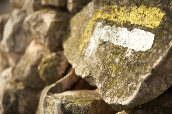 Trail marker on stone wall indicating a change in direction