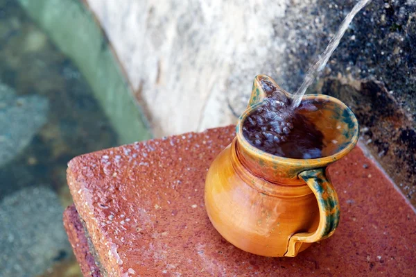 Pottery jug filling up with drinking water from spring — Stock Photo, Image