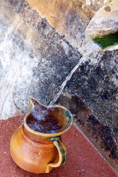 Pottery jug filling up with drinking water from spring — Stock Photo, Image