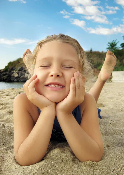 Милая девушка лежит на песчаном пляже и смеется — стоковое фото
