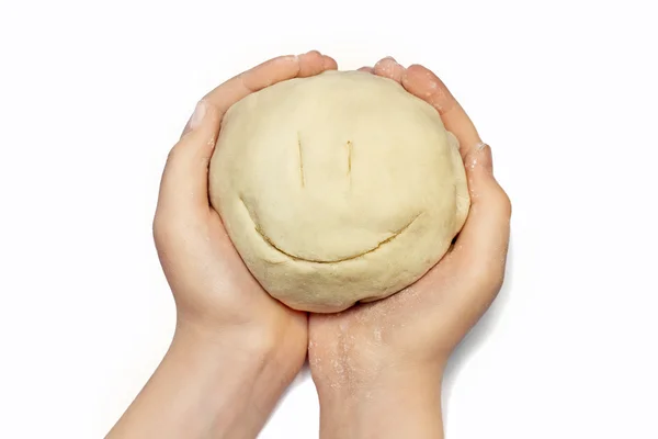 Leende ansikte från degen för bakning i händerna på en liten flicka — Stockfoto