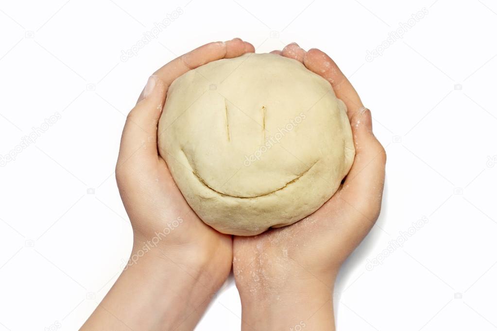 smiling face from the dough for baking in hands of a little girl