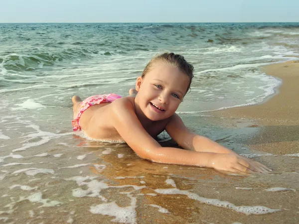 Adorable girl is lying on a sandy beach — Stock Photo, Image