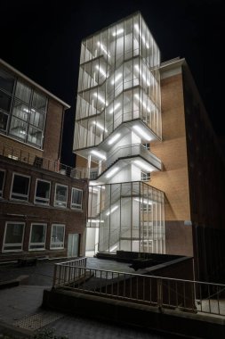 Bu yeni merdiven yenilenmiş bir binanın yanına eklendi, merdiven bir asansörün etrafında dönüyor.