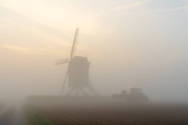 Sabahın erken saatlerinde sislerin içinde güzel bir yel değirmeni var. Güneş gökyüzünden doğuyor.