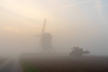 Sabahın erken saatlerinde sislerin içinde güzel bir yel değirmeni var. Güneş gökyüzünden doğuyor.