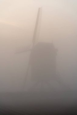 Sabahın erken saatlerinde sislerin içinde güzel bir yel değirmeni var. Güneş gökyüzünden doğuyor.