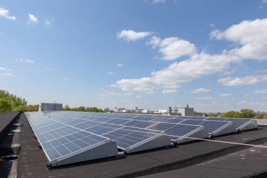 Konut alanındaki bir binada güneşli bir günde çatıda güneş panelleri var.