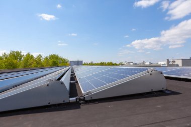 Konut alanındaki bir binada güneşli bir günde çatıda güneş panelleri var.