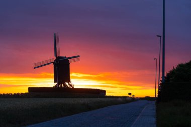 Bu güzel dağ değirmeni Wannegem-Lede Belçika 'da güneş ve bulutların doğuşuyla yer almaktadır..
