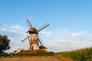 Sabahın erken saatlerinde güneşin gökyüzünde doğduğu güzel bir yel değirmeni vardır.