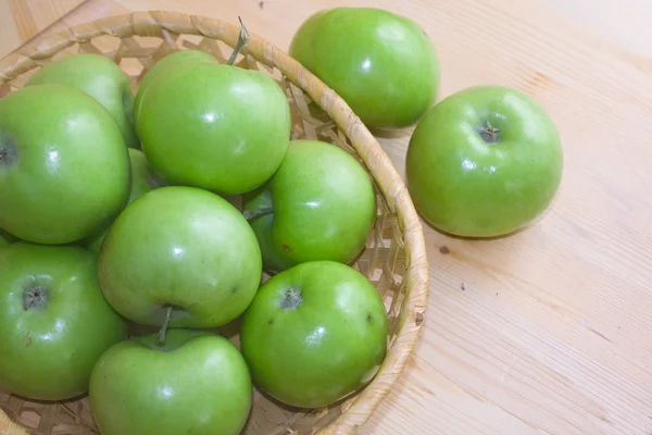 Groene appels in een mand op een lichte achtergrond — Stockfoto