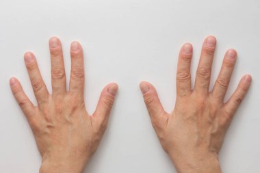 Beyaz arka planda kesilmiş ve renksiz tırnakları olan orta yaşlı kadın elleri.