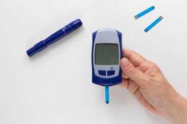 Beyaz arkaplandaki verilerinizi doldurmak için kan testi şeritli glukoz ölçer ve boş ekran kullanan kadının üst görünümü