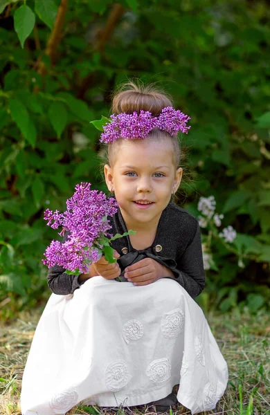 Full length body size smiling cute caucasian little girl child kid of 5 years with lilac wreath on head and lilac bouquet in hands — Fotografia de Stock