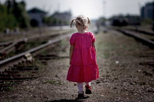 Back of caucasian child kid baby little girl going alone on railroad. Concept abandoned children Fotografias De Stock Royalty-Free