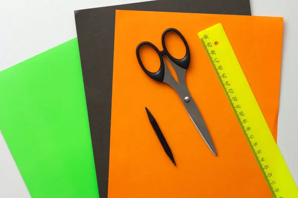 Vista dall'alto di carta verde, nera e arancione per fai da te e forbici, matita e righello su sfondo bianco — Foto Stock
