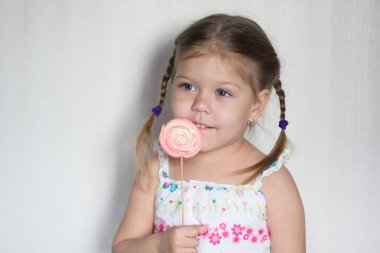 Üç yaşında beyaz arka plana bakan tatlı çubuklu mutlu bir beyaz çocuk portresi.