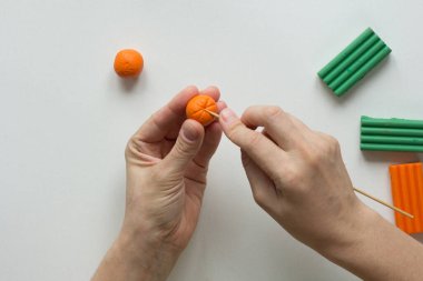 Kadın elleri turuncu topun üzerinde diş çubuğuyla şerit yapıyor. Turuncu meyve yaratmak için.