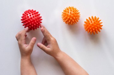 Çocuk eli, beyaz arka planda sivri kırmızı masaj iğnesi topuna dokunuyor.