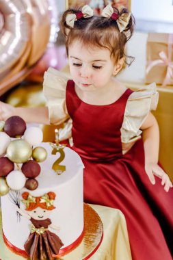 Doğum günü pastasında mum söndürmeye çalışan sevimli bir kızın dikey yüksek açılı portresi. Güzel bebek doğum günü fotoshop 'u