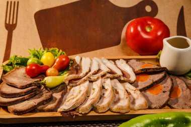 Meat assortment in restaurant with tomatoes, peppers and greens. Copy space for logos and text