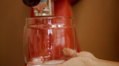 Barista kahve makinesinde taze kahve çekirdeklerini öğütüyor ve plastik kaba kahve dolduruyor.