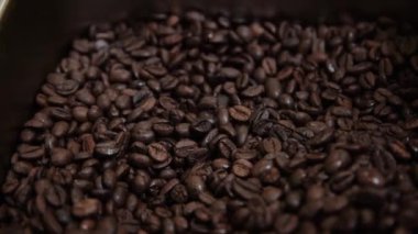 Sarı elbiseli bir kadının kahve çekirdeklerini metal kepçeyle karıştırdığı görüntüler.