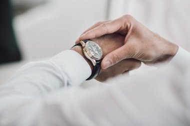 Damadın elleri düğün günü saati kontrol ediyor. Damat, düğün töreninden önce odasında hazırlanıyor.