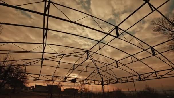 Hermosa puesta de sol a través de las construcciones metálicas abandonadas y dañadas — Vídeos de Stock