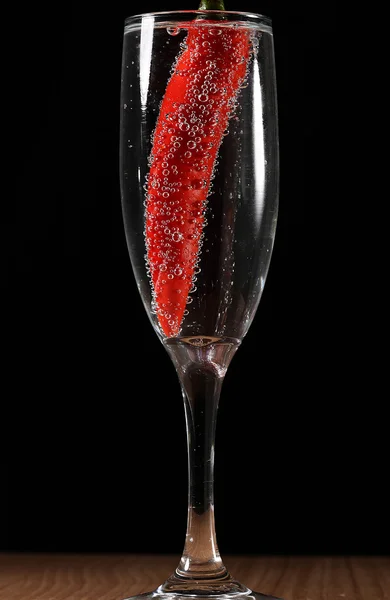 Red pepper dropped into champagne glass with bubbles — Stock Photo, Image