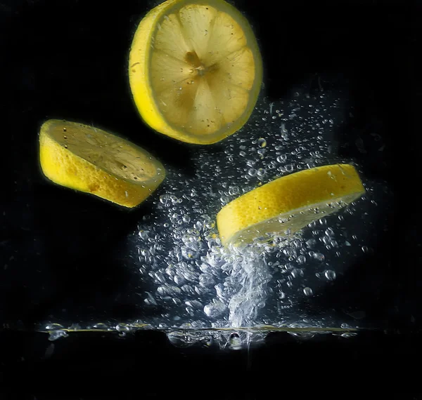 Lemon slices make bubbles in the water — Stock Photo, Image