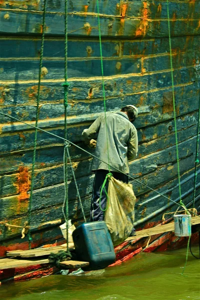 Man op het werk, schilderij van een boot — Stockfoto