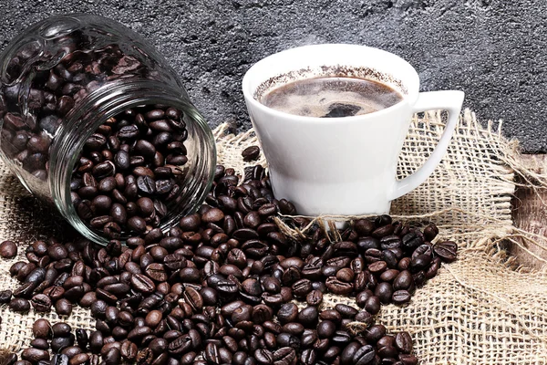 Pouring coffee beans on jute, stone background — Stock Photo, Image