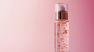 Pembe arka planda altın şişede cilt jölesi