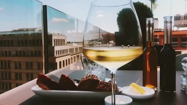 Glas witte wijn buiten, uitzicht op de stad — Stockvideo
