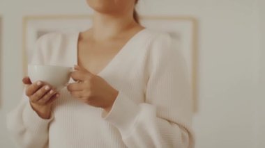 Soğuk sonbahar ya da kış mevsiminde evde elinde çay ya da kahveyle sıcak bardak tutan bir kadın.