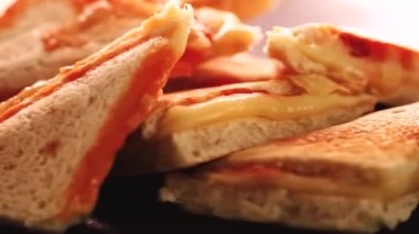 Sandviç tost makinesinde pişirilmiş sıcak üçgen peynirli sandviçler, ev yapımı konforlu yemekler.